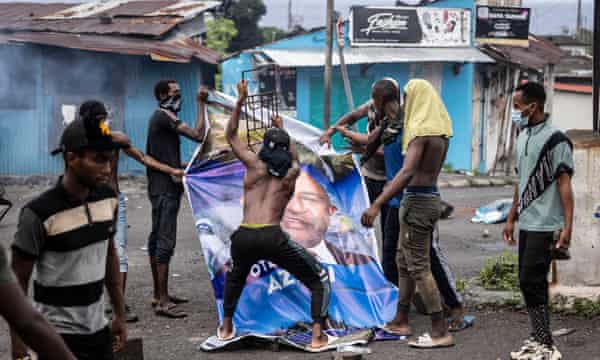 Opposition supporters destroy a billboard image of Comoros President Azali Assoumani and his Convention for the Renewal of Comoros party.