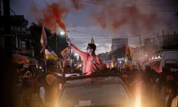 Madagascar President Andry Rajoelina rides in a pickup truck holding a flare as he greets supporters during his re-election campaign, in Toamasina, November 2023.