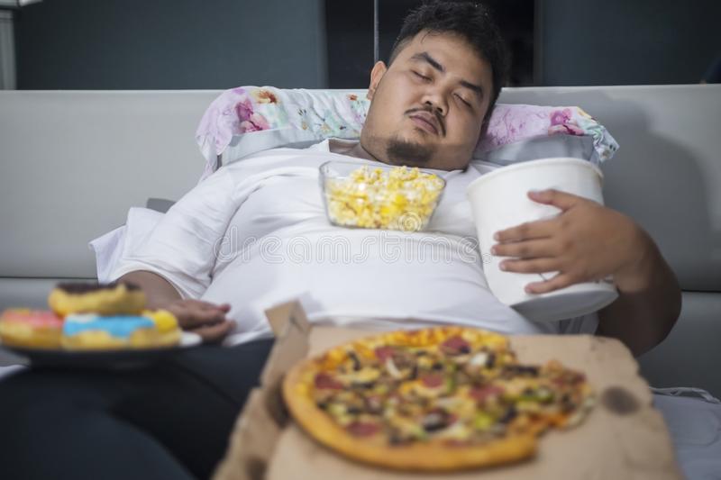 unhealthy-lifestyle-concept-asian-obese-man-eating-junk-foods-sleeping-bed-asian-obese-man-sle...jpg
