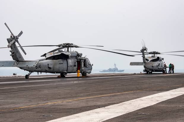 US navy sailors conduct pre-flight checks on an MH-60R Sea Hawk in drills in the South China Sea.