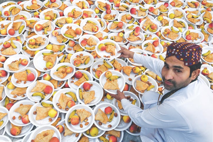  LAHORE: A volunteer prepares iftar at the Data Darbar shrine on the first day of Ramazan, on Thursday.—AFP 