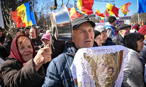 A Moldovan demonstrator bangs a spoon on a dish next to another holding a religious icon during a protest on behalf of the Sor opposition party in Chisinau on 12 March 2023.