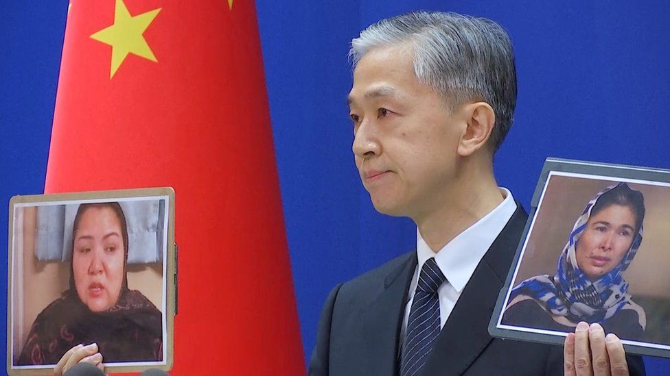 Chinese Foreign Ministry spokesman Wang Wenbin holds pictures while speaking during a news conference in Beijing, China February 23, 2021,