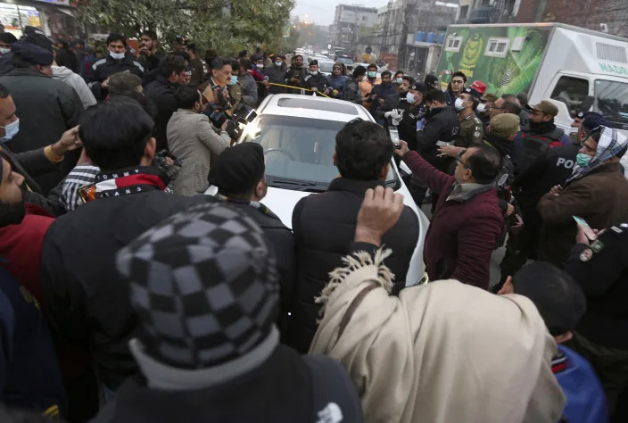 Police officers and journalists gather around the car of local journalist Husnain Shah at the site of a shooting, in Lahore, Pakistan, Monday, Jan. 24, 2022. Unidentified gunmen riding on a motorcycle shot and killed Shah in the eastern city of Lahore on Monday before fleeing the scene, a police official and representatives of journalists said. (AP Photo/K.M. Chaudary)